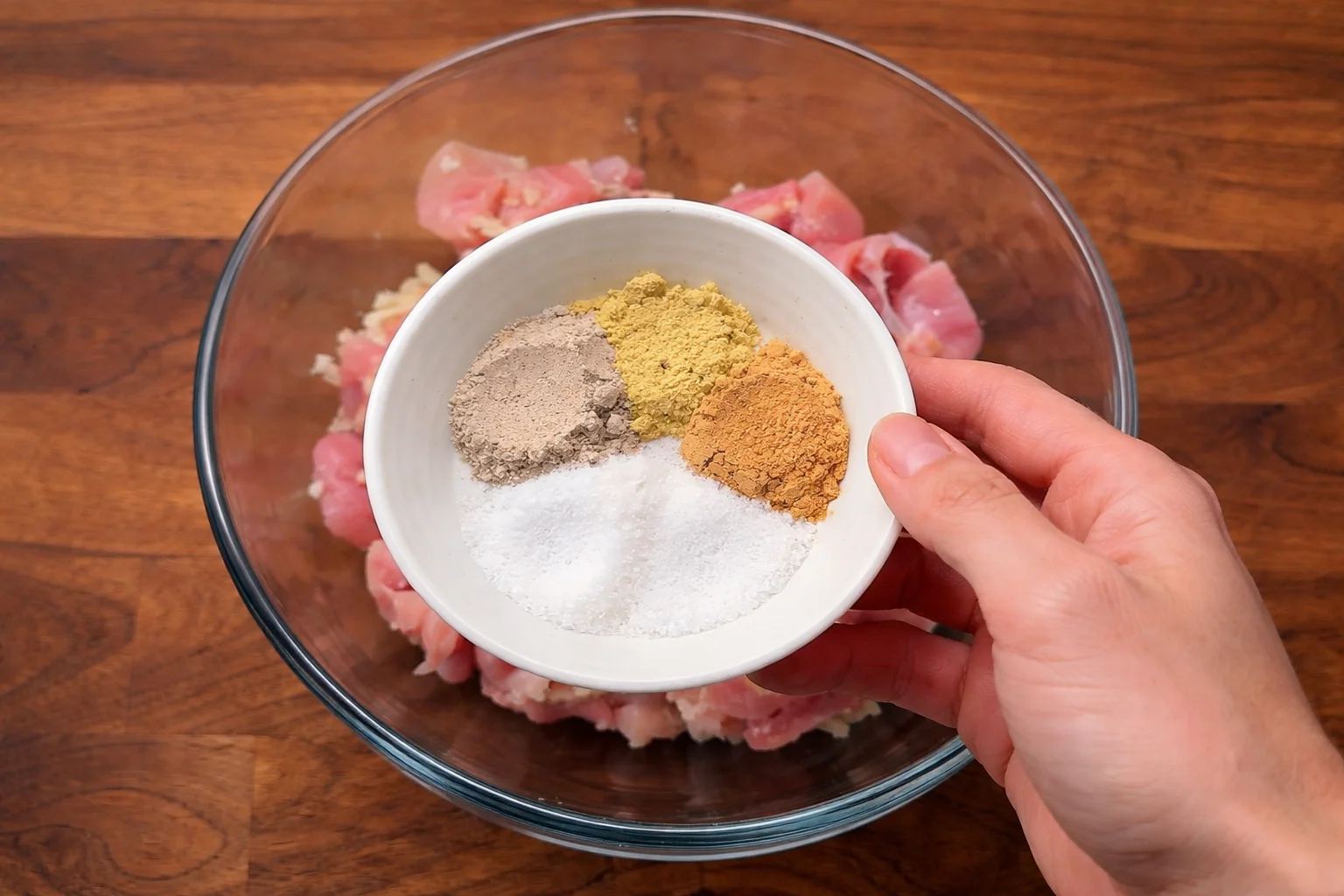Salt and spices being added to marinated chicken