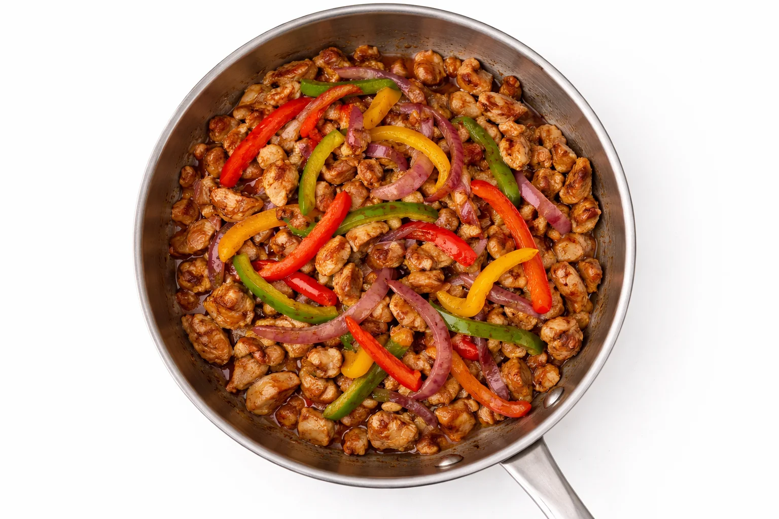 Cooked chicken mixed with sautéed bell peppers and onions in skillet for crispy chicken quesadillas