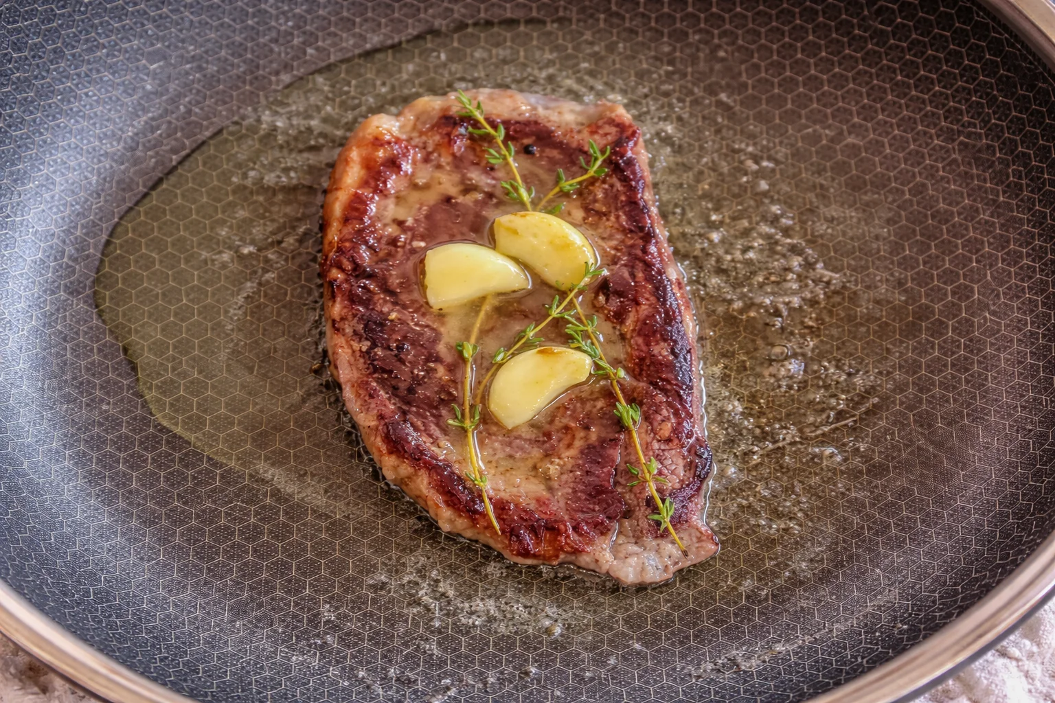 Butter and thyme melting over steak in skillet for basting