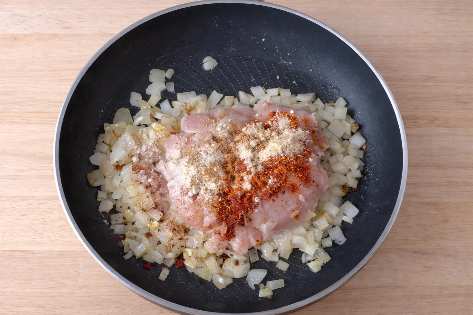 Chicken cooking with onions and spices in a skillet