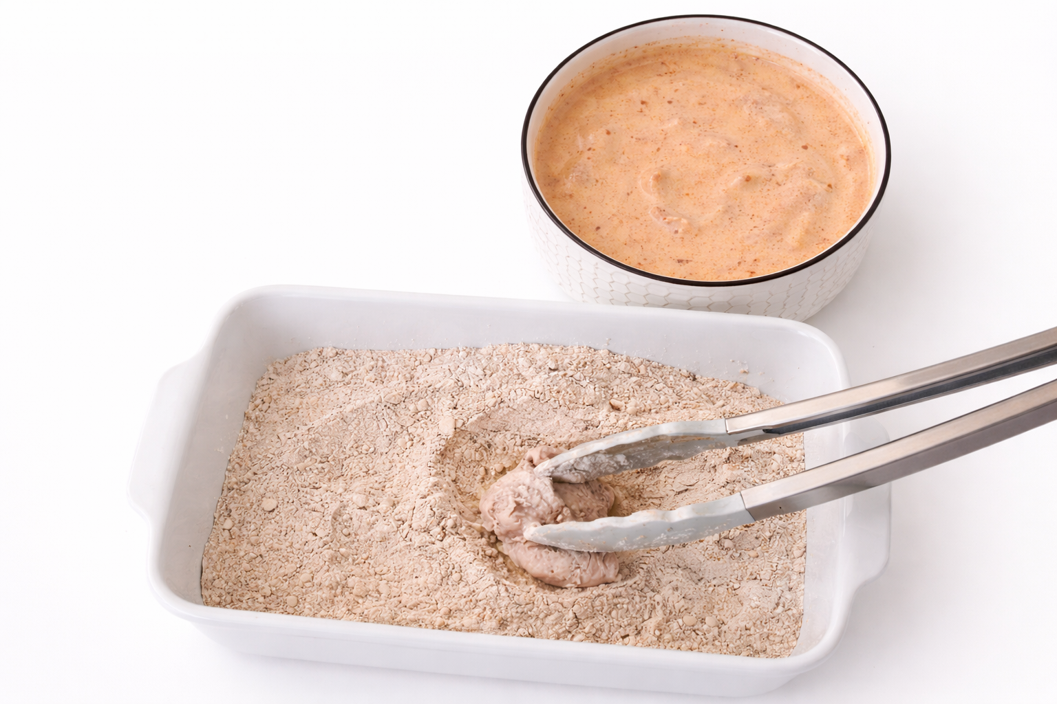 Marinated chicken being coated in seasoned flour mixture