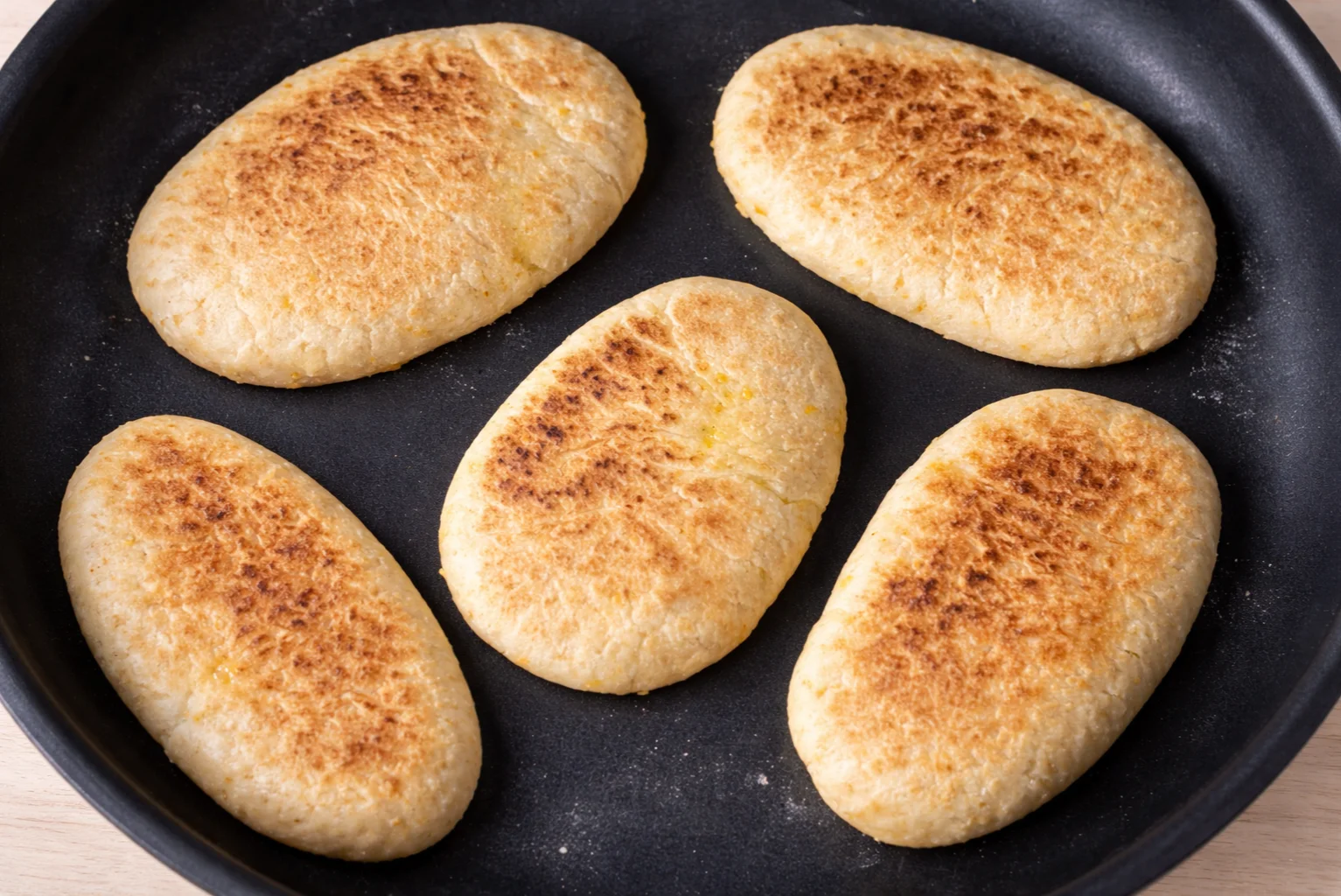 Oval flatbread cooking in a skillet until golden brown