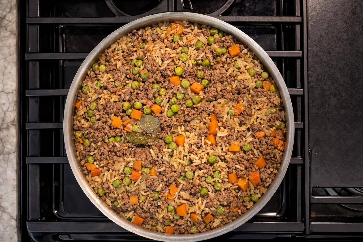 Fully cooked one pot beef and rice with peas and carrots in a stainless steel skillet