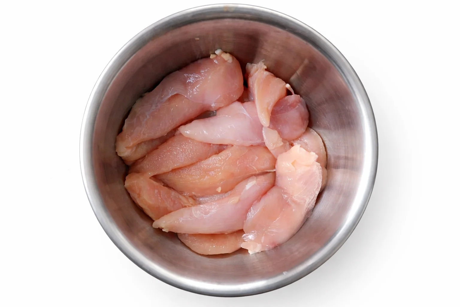 Raw chicken tenders in a stainless steel bowl ready to be seasoned