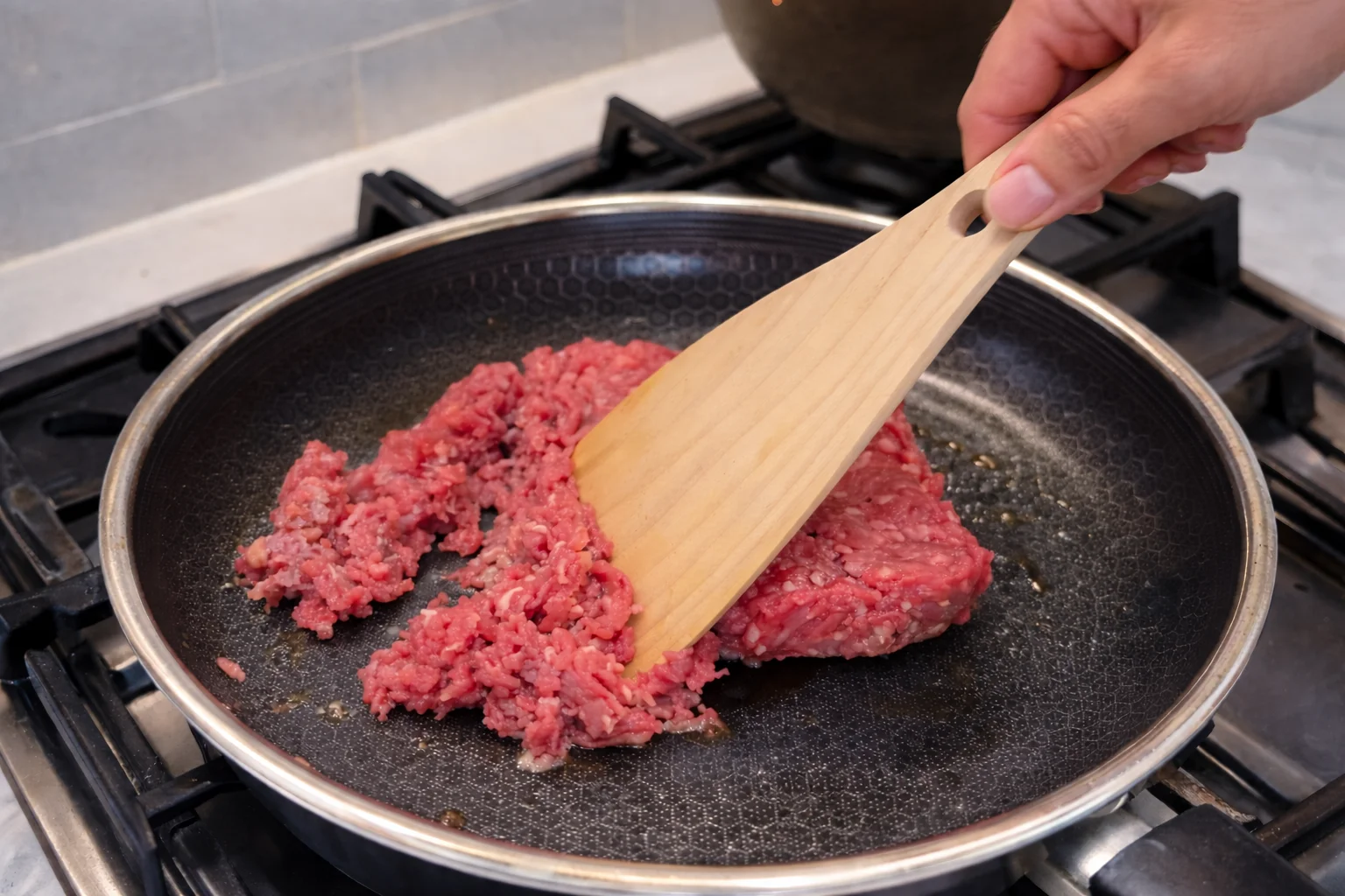 Tomato paste being added to seasoned ground beef in a skillet to build rich taco flavor