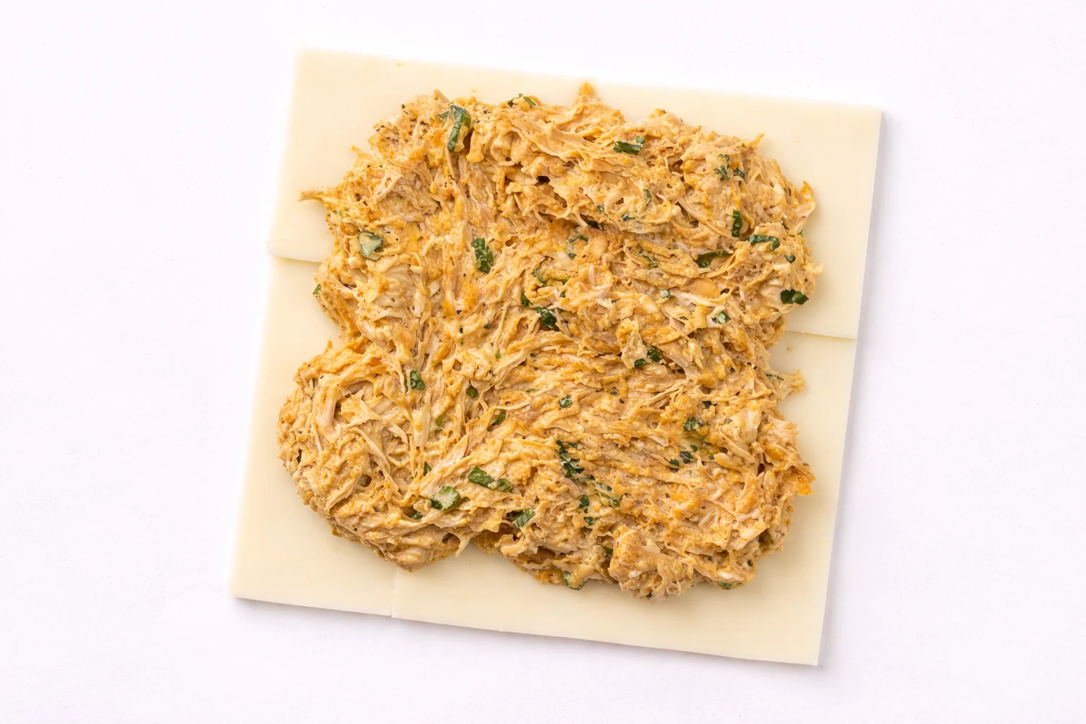 Buffalo chicken layered over cheese slices ready for baking sliders