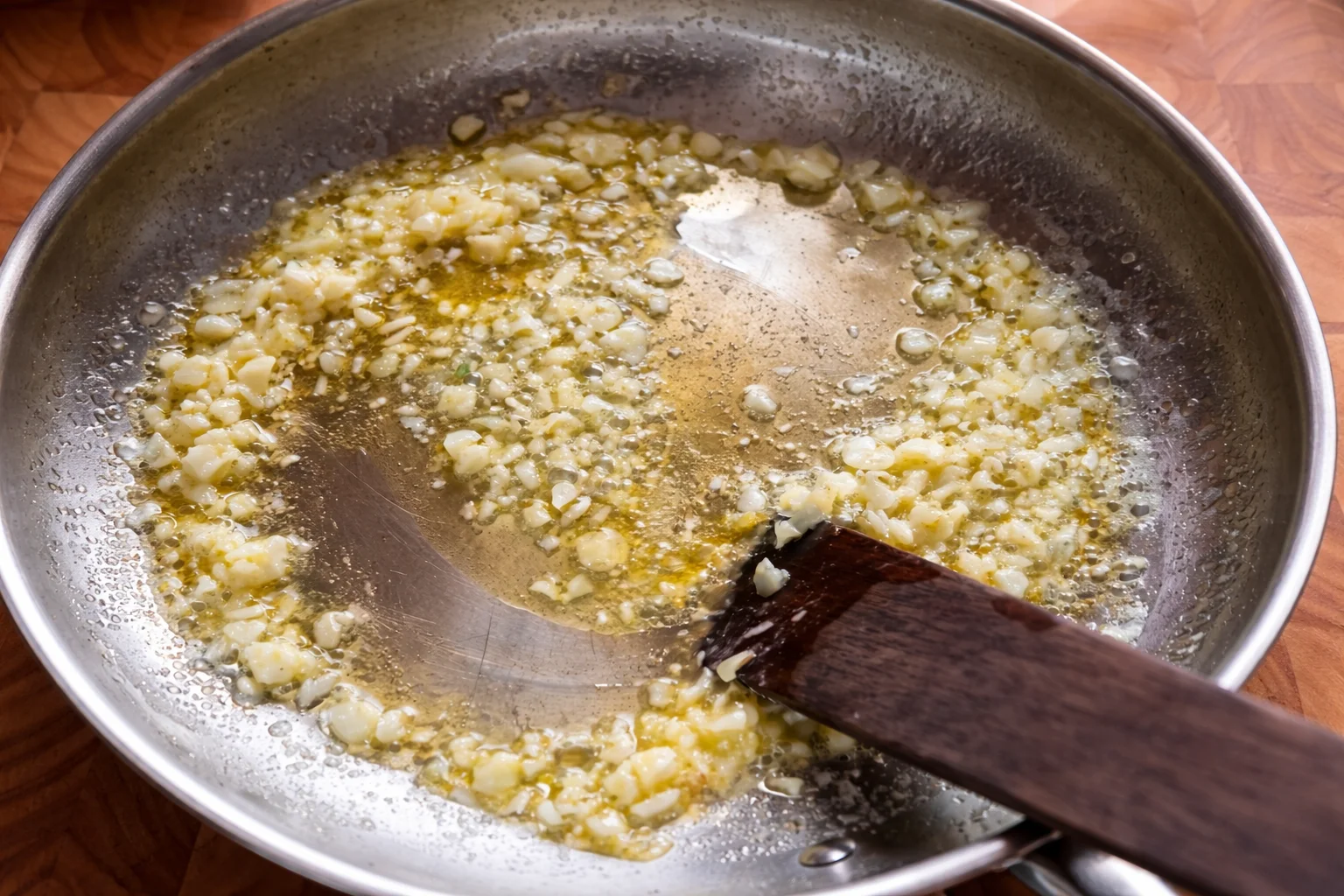 Minced garlic gently sautéing in melted butter to make garlic parmesan sauce