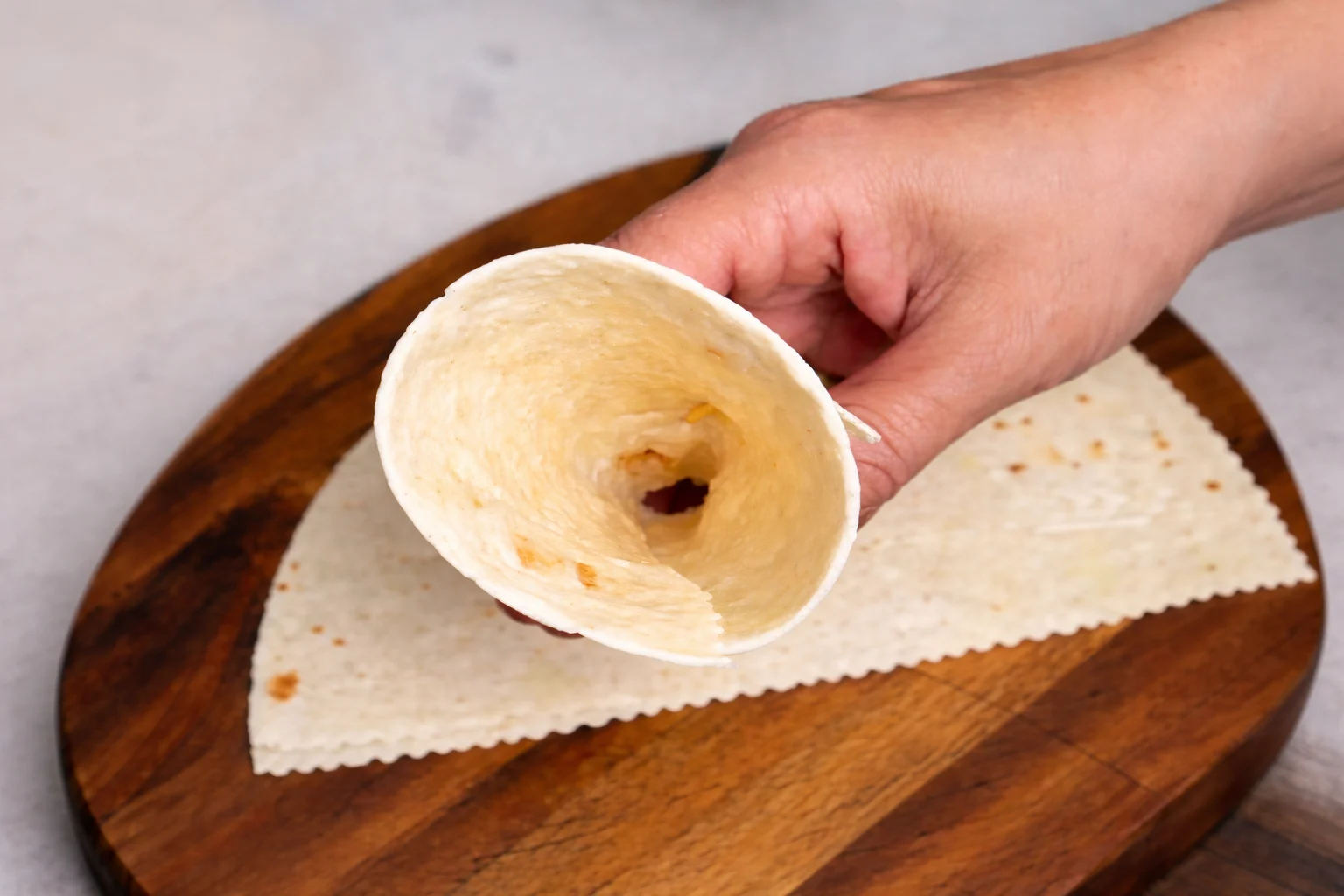 Shaping a flour tortilla into a cone for air fryer pizza cones