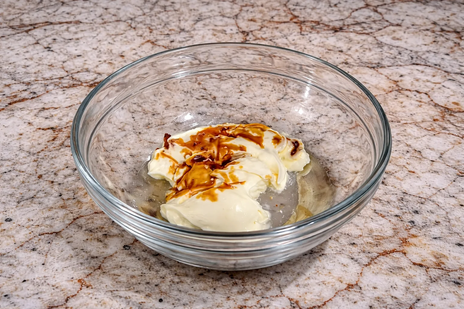 Soy sauce and melted butter being added to mayonnaise in a glass bowl for beef cone dipping sauce