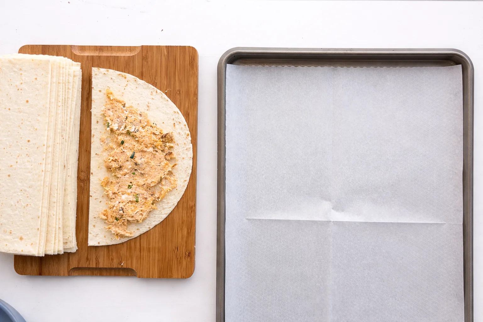 Buffalo chicken filling spread over tortilla half before rolling into cone