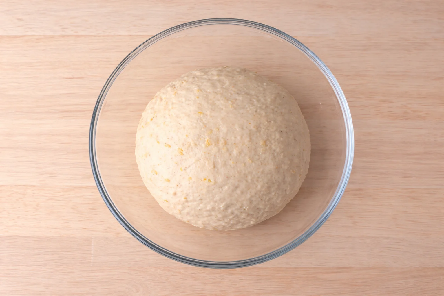 Smooth dough ball resting in a glass bowl after kneading