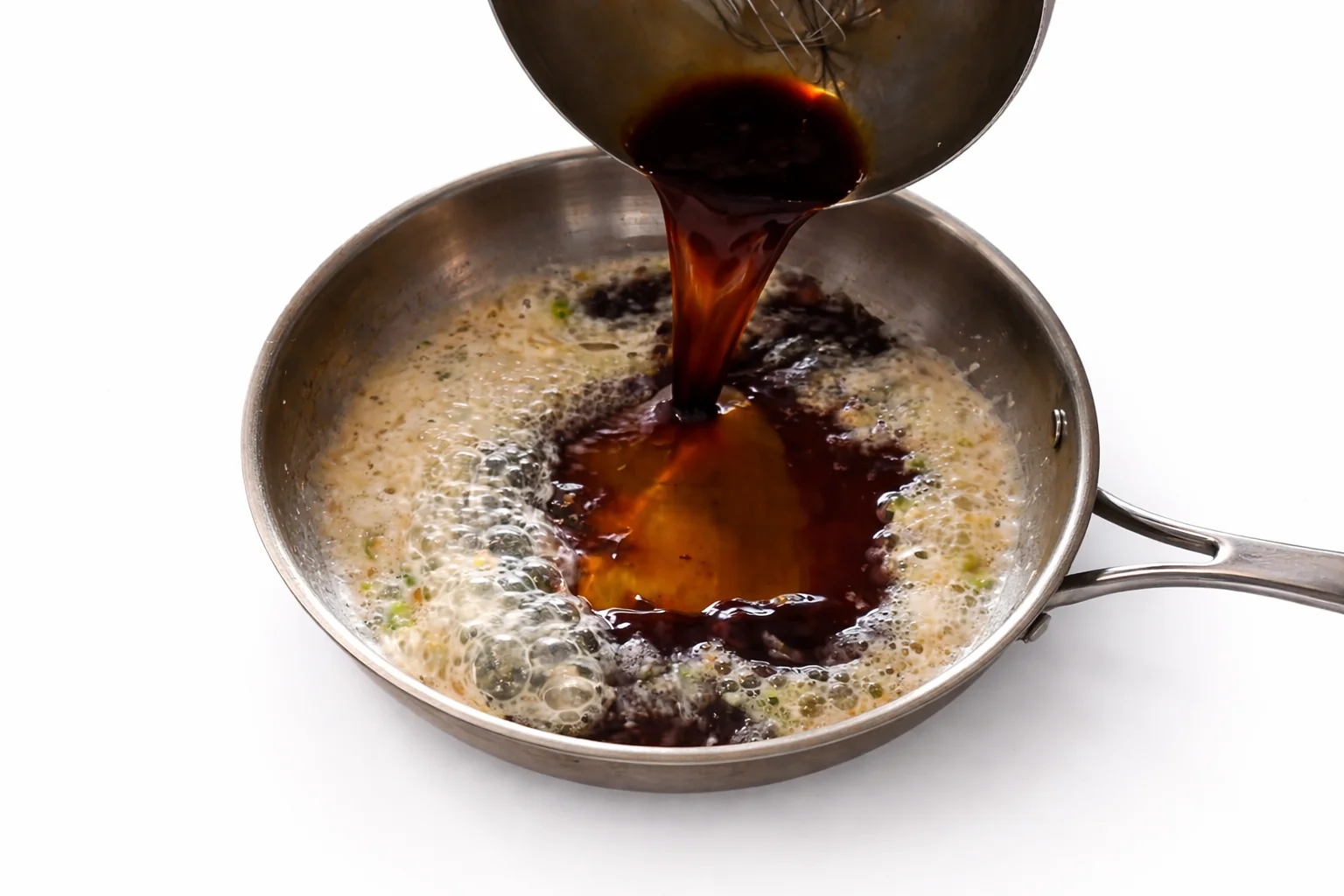 Honey garlic sauce being poured into pan with sautéed garlic mixture