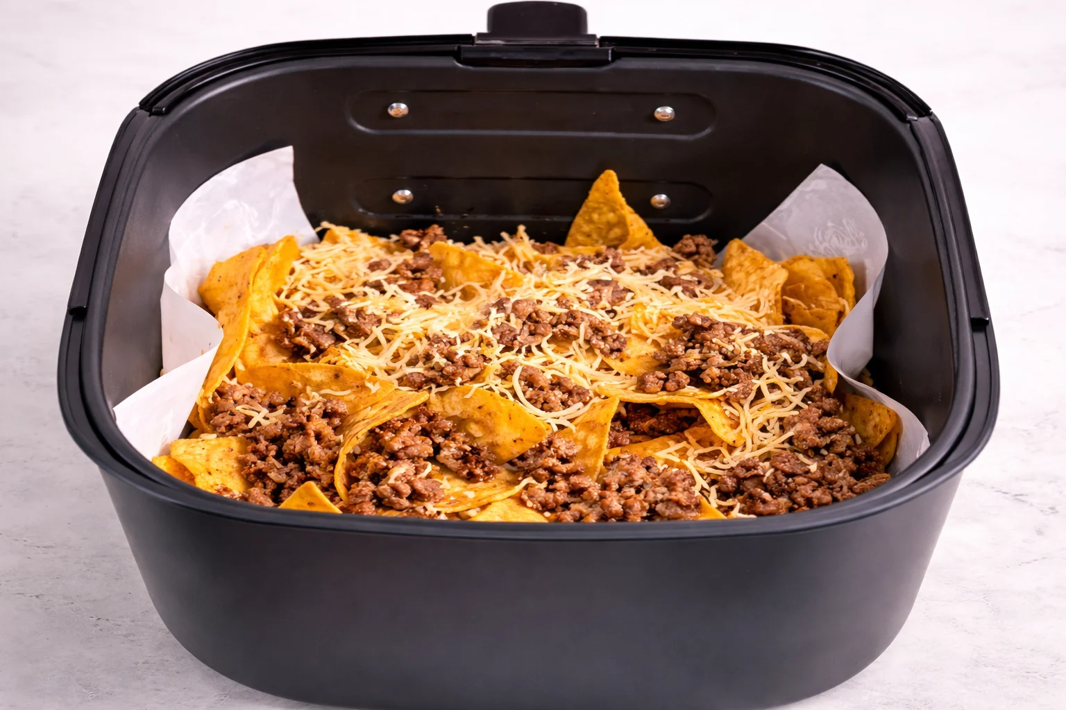 A generous sprinkle of shredded cheese melts between the layers and helps bind the nachos together.