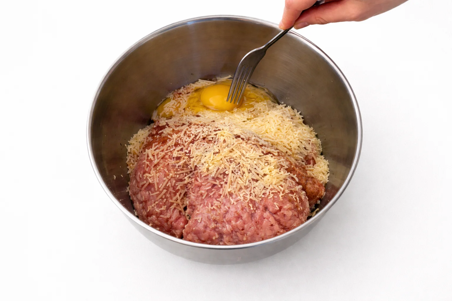 Ground chicken mixed with egg and Parmesan cheese in a stainless steel bowl for crispy baked chicken nuggets