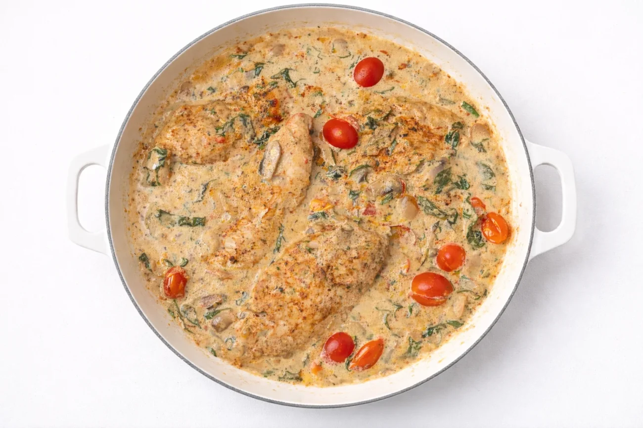 creamy tuscan chicken with garlic cream sauce mushrooms spinach and cherry tomatoes in skillet