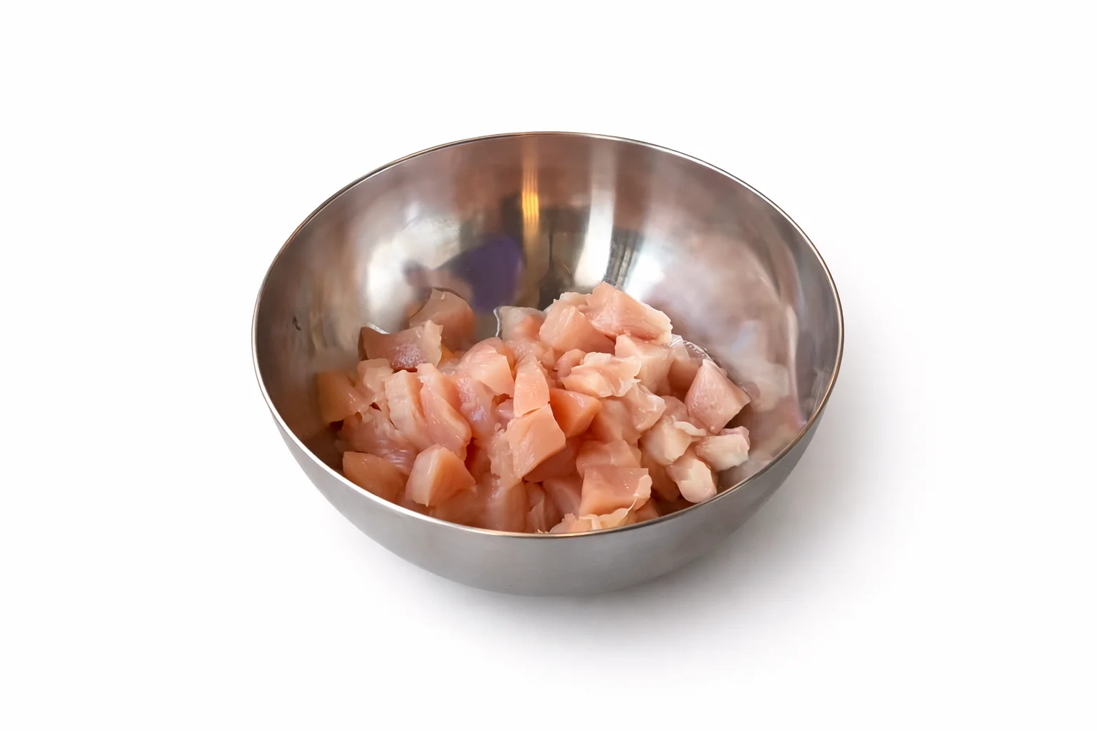 fresh chicken breast cut into small bite sized pieces in a stainless steel mixing bowl