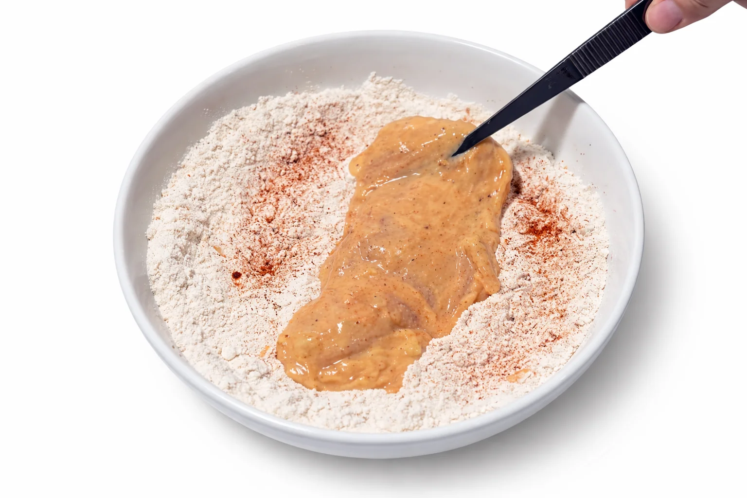 Marinated chicken placed into seasoned flour coating