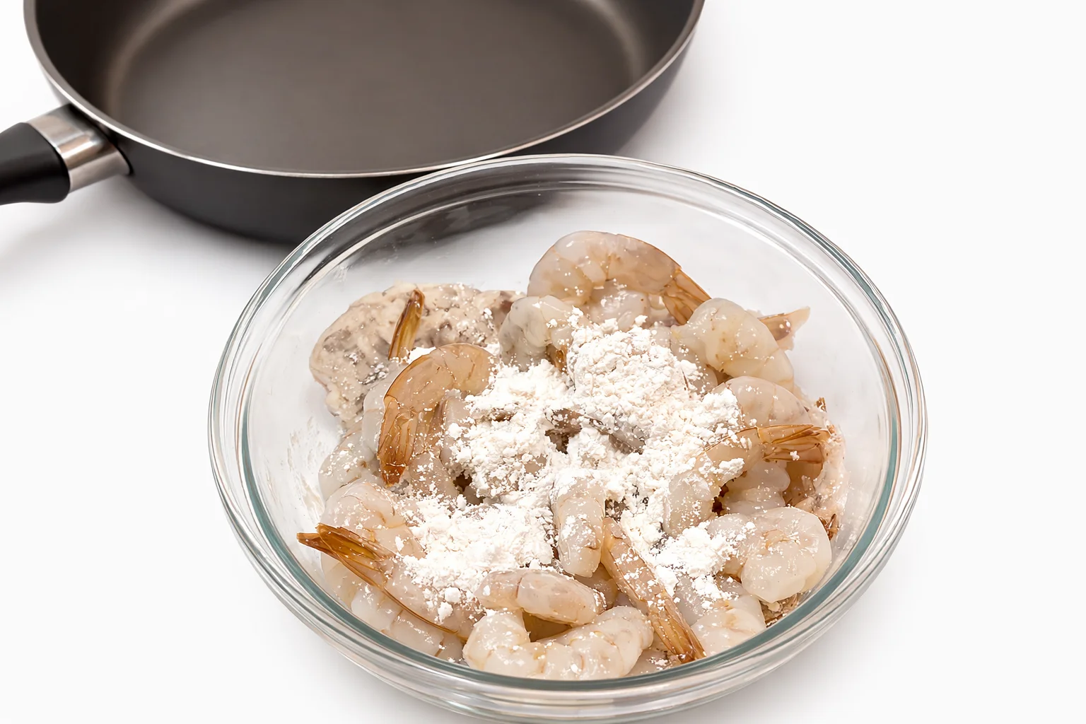 raw shrimp coated with flour in a glass bowl before seasoning