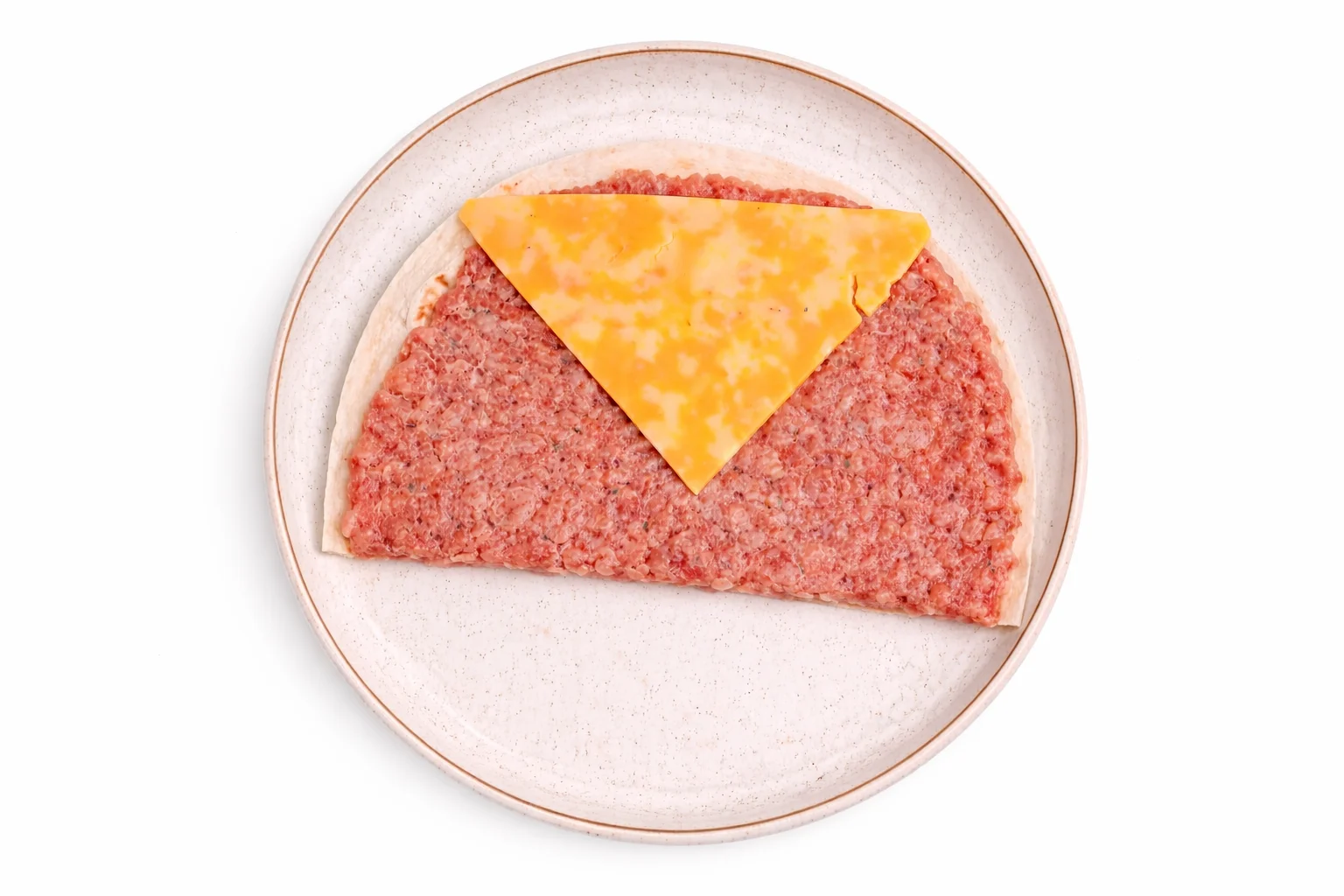 slice of colby jack cheese placed on top of sausage covered tortilla before rolling into breakfast tortilla cones