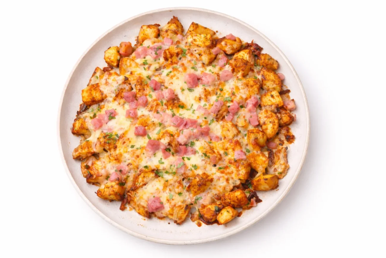 air fryer cheesy potato bites topped with melted cheese bacon and parsley served on a plate