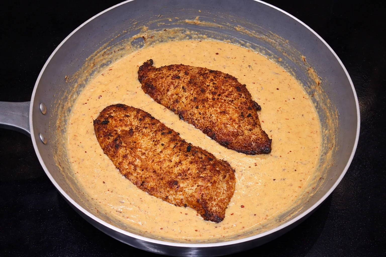 Cajun chicken finished in creamy sauce inside a pan