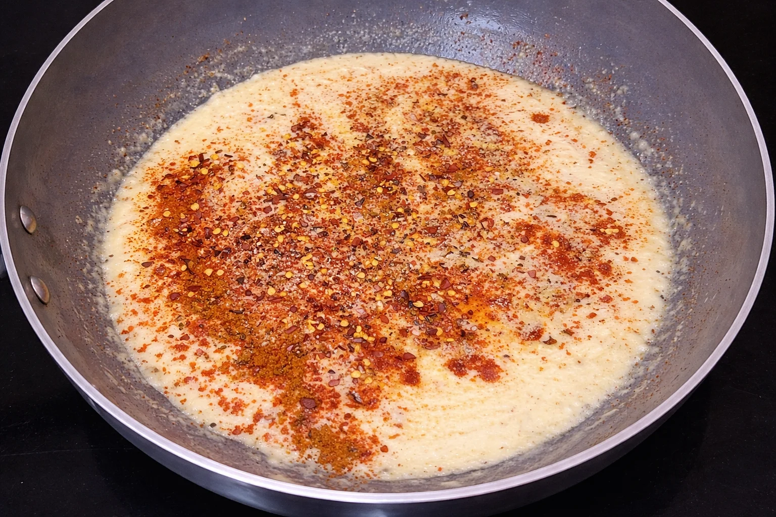 Creamy Cajun sauce simmering in a pan with spices