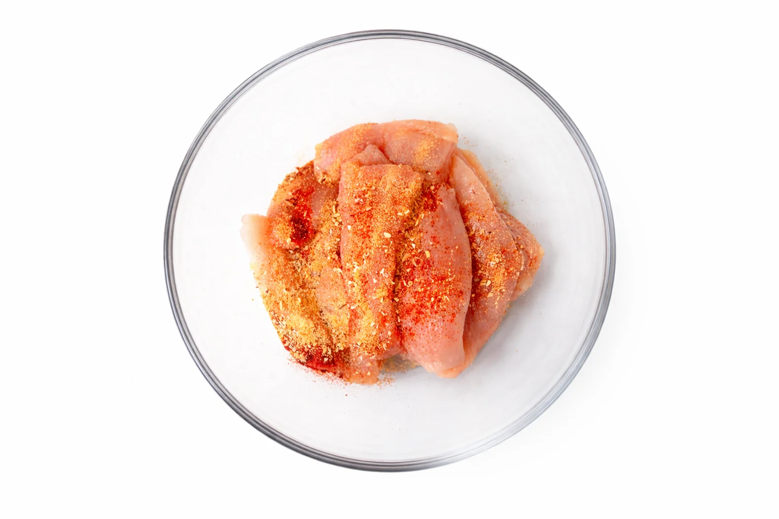 raw chicken tenders coated with seasoning in a bowl