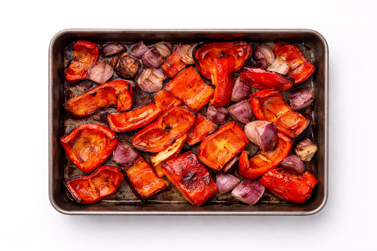 roasted red peppers and onions with charred edges on a baking tray